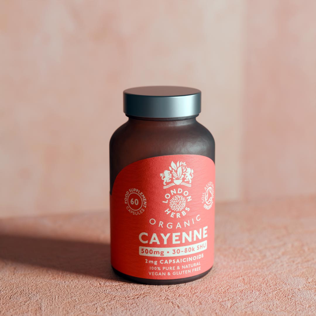Bottle of London Herbs Organic Cayenne Pepper Capsules capsules herbal supplement on a plaster surface.